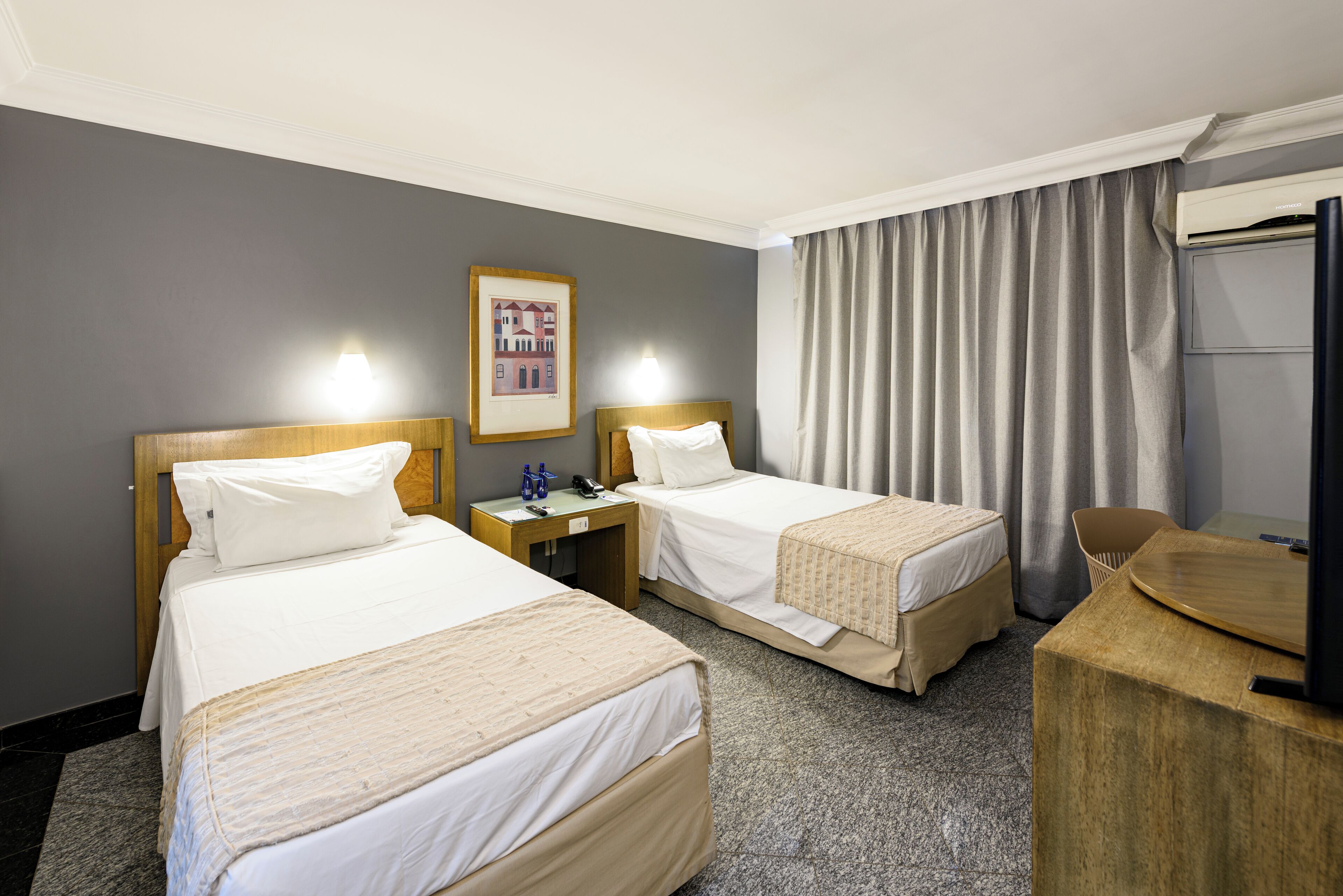Une chambre d’hôtel avec deux lits simples, un bureau, une chaise et un téléviseur.