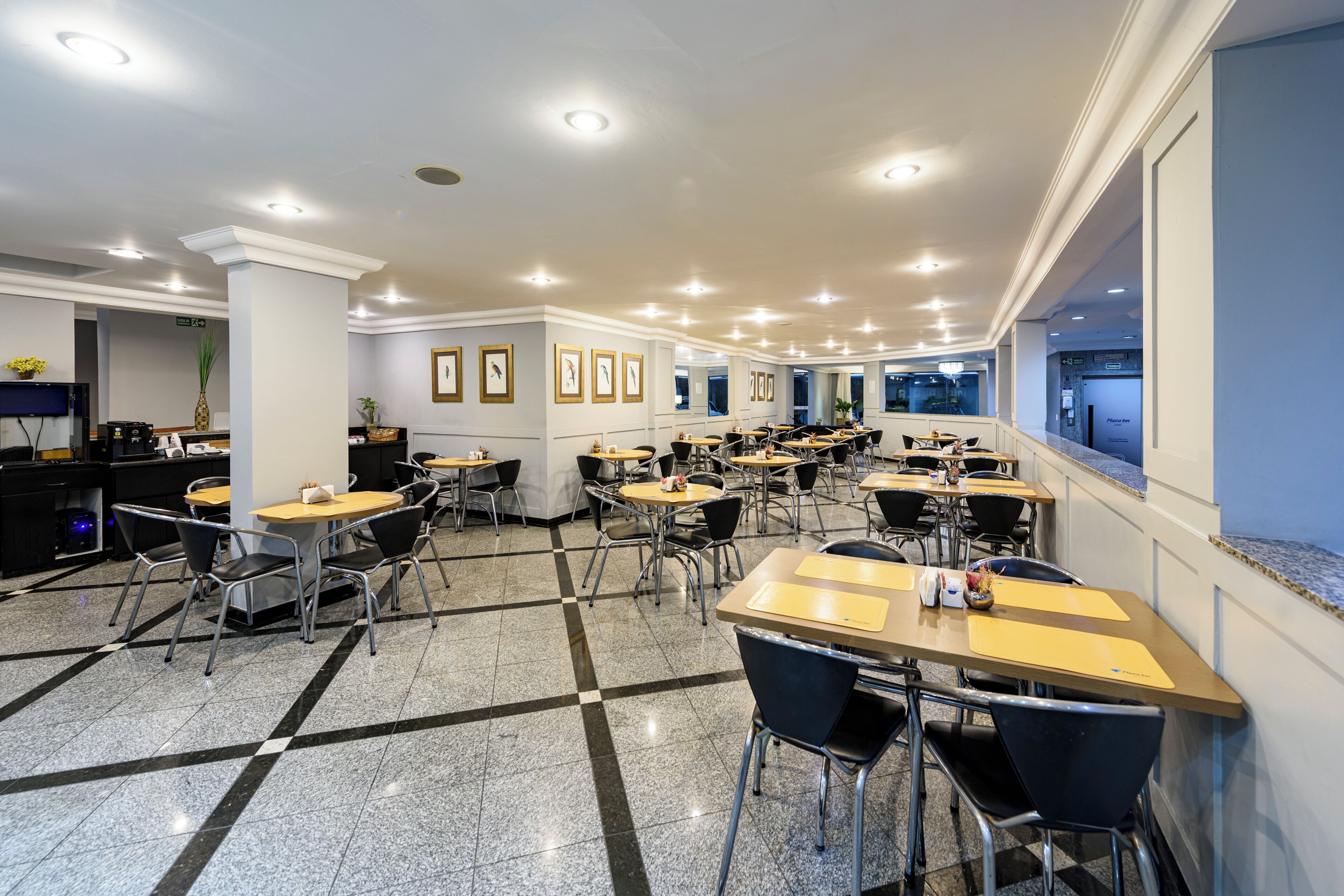 A spacious dining area with multiple tables and chairs, a polished floor, and framed artwork on the walls.