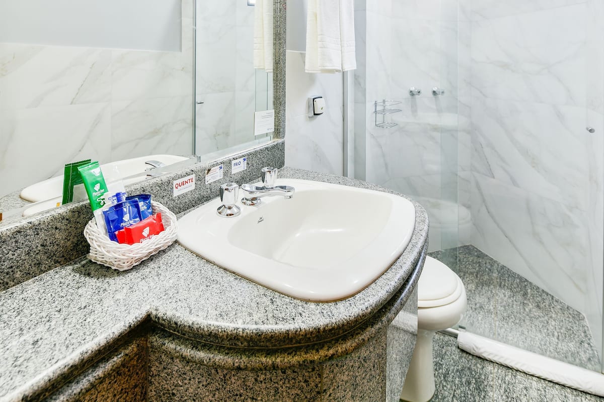 Ein Badezimmer mit Marmorwaschbecken, Toilette, Dusche und einem großen Spiegel.
