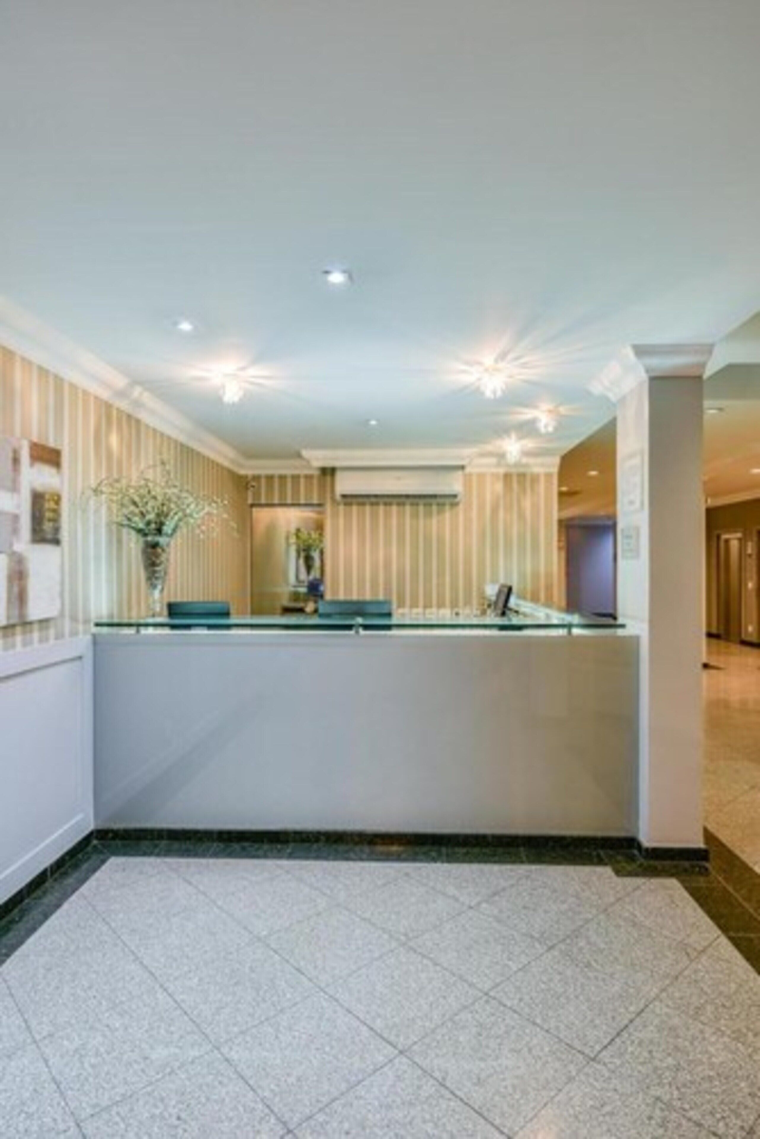 A reception area with a reception desk, a vase of flowers, and a tiled floor.