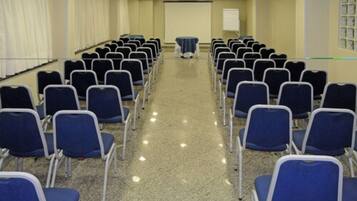 A conference room with rows of blue chairs and a whiteboard at the front.