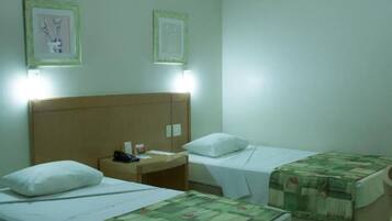Una habitación de hotel con dos camas individuales, cada una con una almohada y una mesita de noche. Hay cuadros enmarcados en la pared sobre las camas.