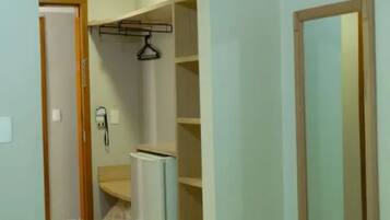 Um quarto com cama, guarda-roupa e espelho.