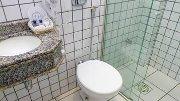 A bathroom with a granite sink, white toilet, and a glass shower enclosure.