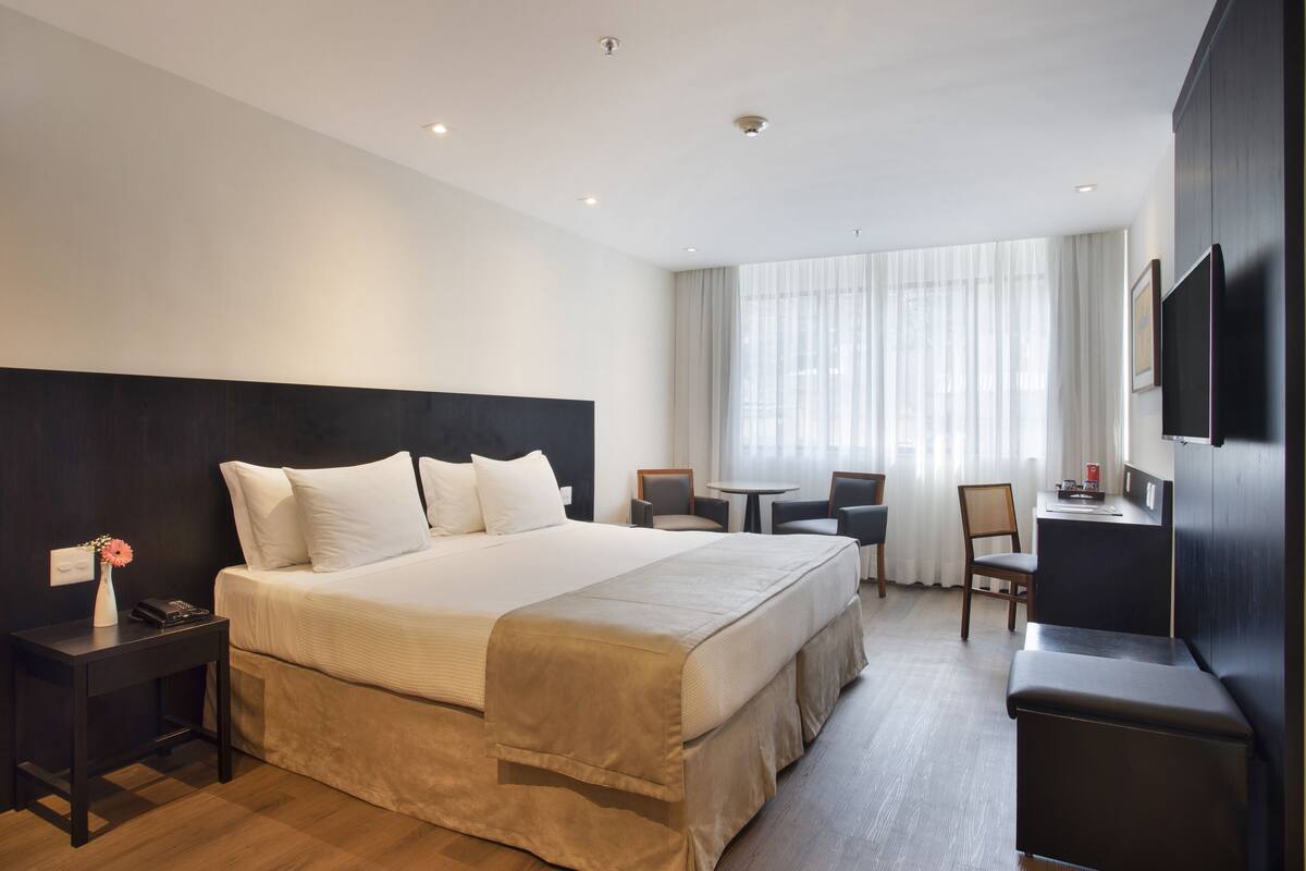Una habitación de hotel moderna con una cama grande, un escritorio y un televisor.