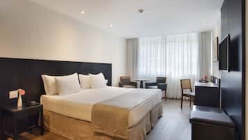 A modern hotel room with a large bed, a desk, and a TV.