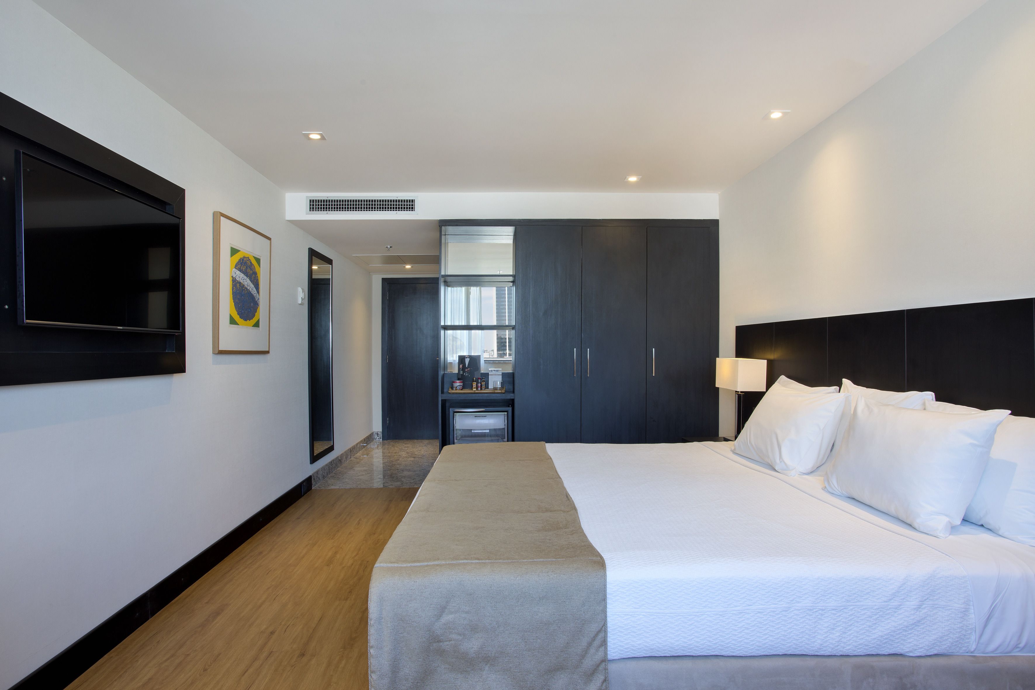 Habitación de hotel con una cama grande, un televisor de pantalla plana, un minibar y vista a la ciudad.