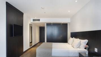 A modern bedroom with a large bed, dark wood wardrobe, and a flat-screen TV.