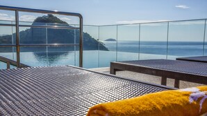 A balcony with a metal railing, a yellow towel, and a view of the sea and a distant island. - Windsor Leme Hotel (Rio de Janeiro)