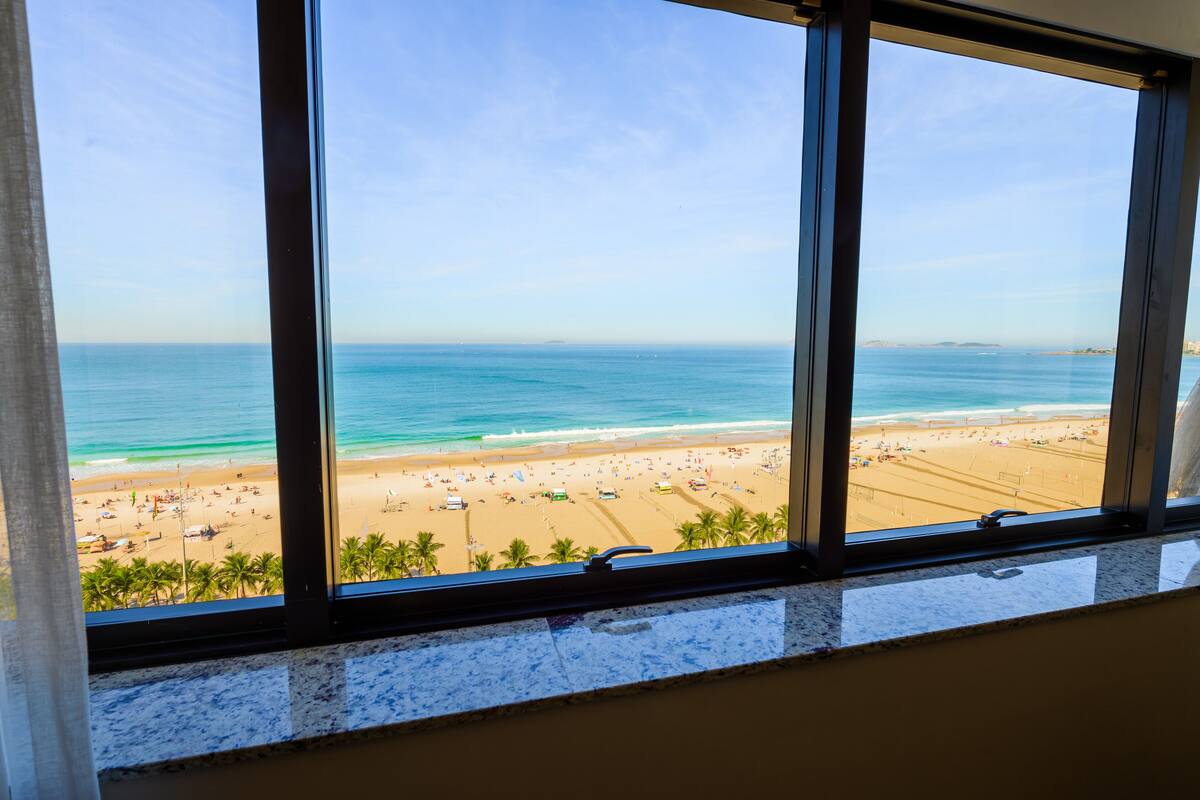 Vista de una playa desde una ventana, con cielo despejado.