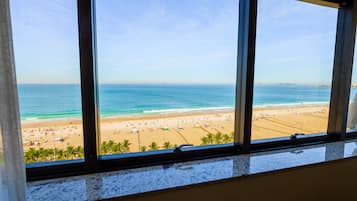 Vista de una playa desde una ventana, con cielo despejado.
