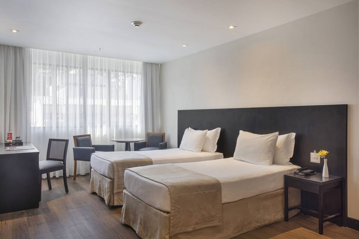 Habitación de hotel con dos camas, un escritorio, sillas y una mesita.