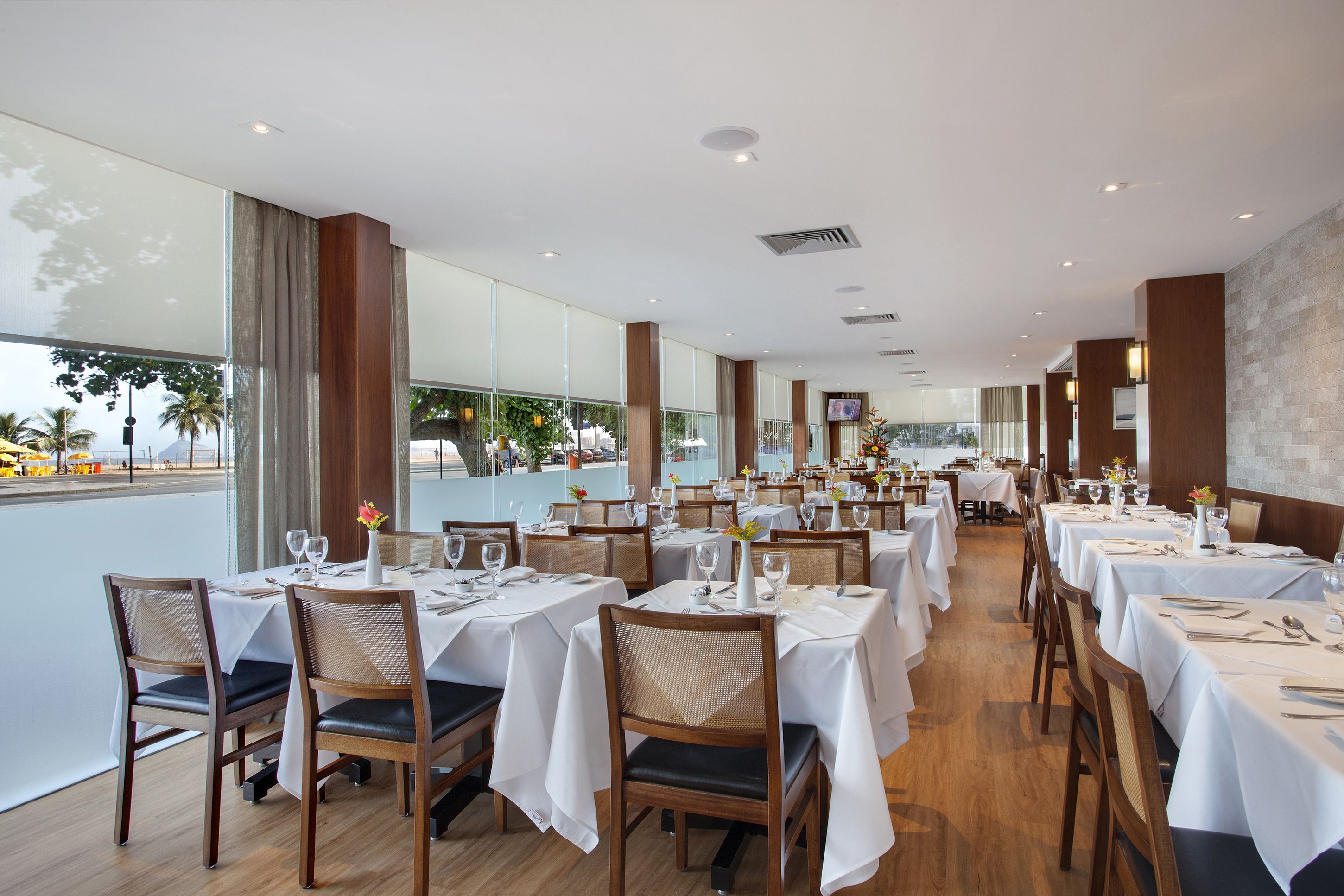 A restaurant with multiple tables set for dining, large windows offering a view, and a modern interior design.