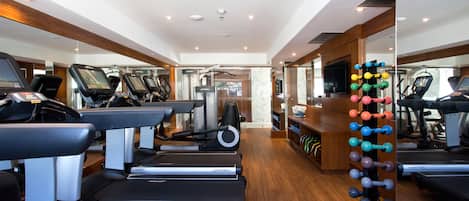 A gym with treadmills, elliptical machines, and a weight rack.