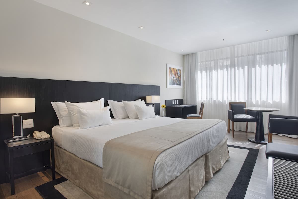 Una habitación de hotel moderna con una cama grande, mesitas de noche, un escritorio y una silla.