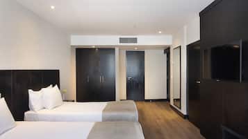 Quarto de hotel moderno com duas camas, uma televisão de tela plana e um espelho grande.