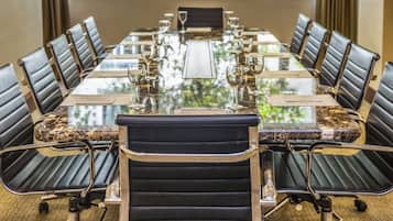 Una sala de conferencias con una mesa de cristal, sillas de cuero y copas de vino.