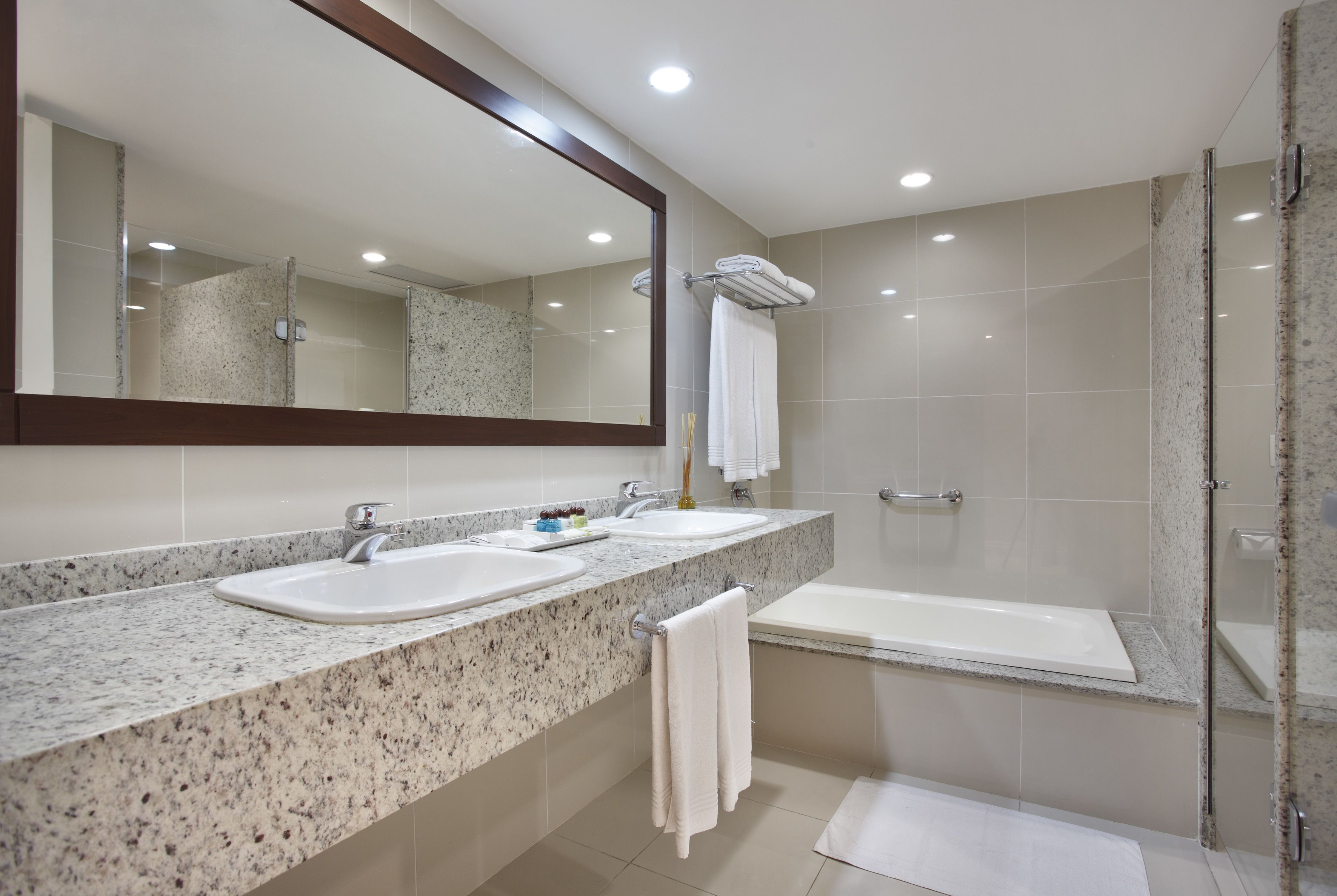 Uma casa de banho moderna com duas pias, um espelho grande e cabine de duche com vidro.