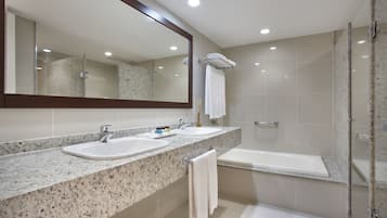 Uma casa de banho moderna com duas pias, um espelho grande e cabine de duche com vidro.