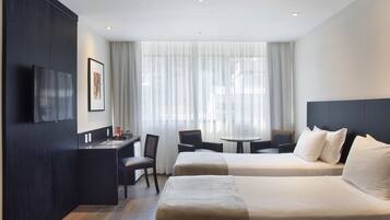 Quarto de hotel com cama, escrivaninha e cadeira.