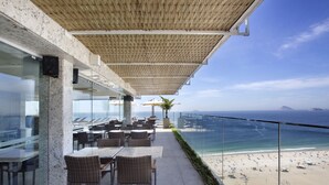 Una terraza con mesas y sillas que da a una playa y al océano.