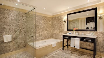 A modern bathroom with a glass-enclosed shower, a freestanding bathtub, and a vanity with a large mirror.
