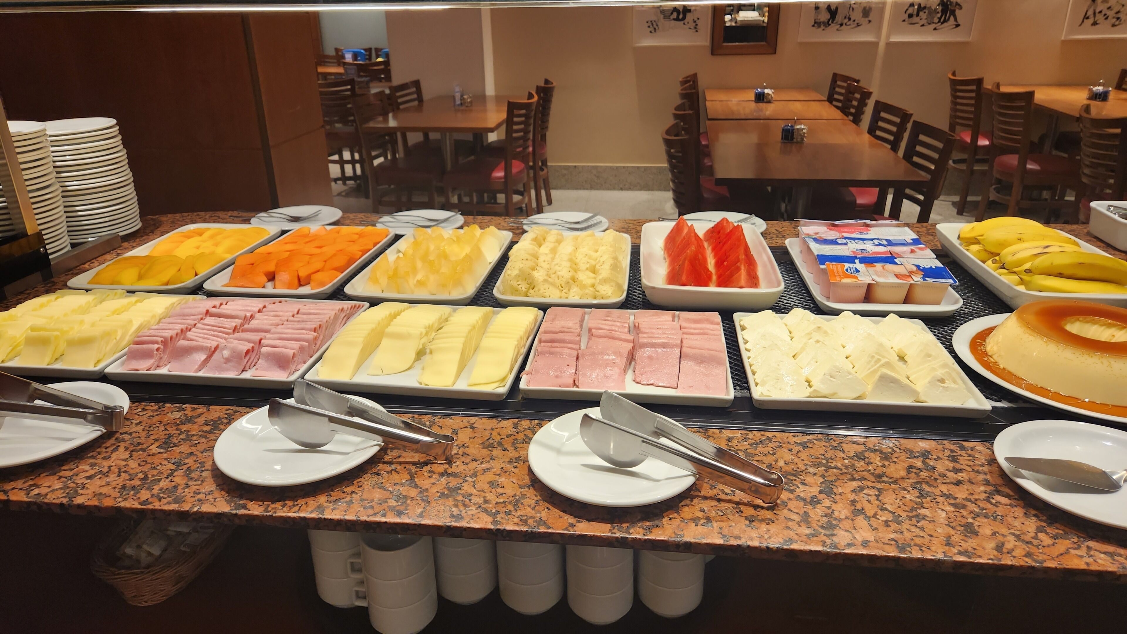 A buffet with various food items including fruits, cheeses, and meats.