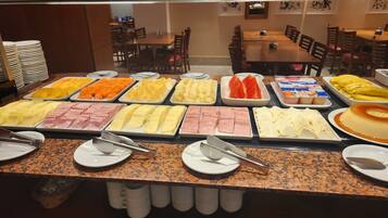 A buffet with various food items including fruits, cheeses, and meats.
