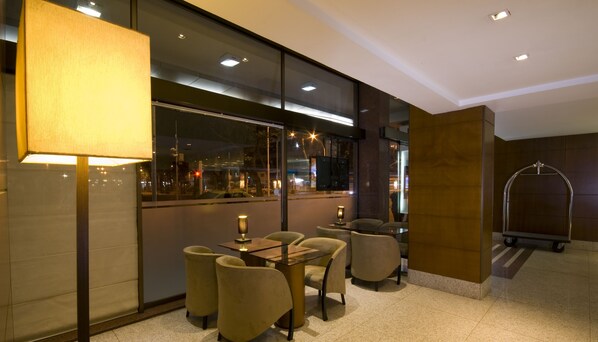 Un interior moderno con un comedor que incluye una mesa y sillas, un ventanal con vistas a la ciudad y una zona de ducha con mampara de vidrio.
