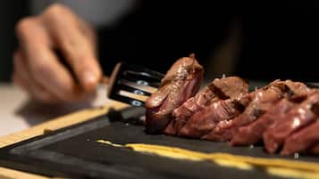 Eine Person schneidet Fleisch auf einer schwarzen Schneidebrett.