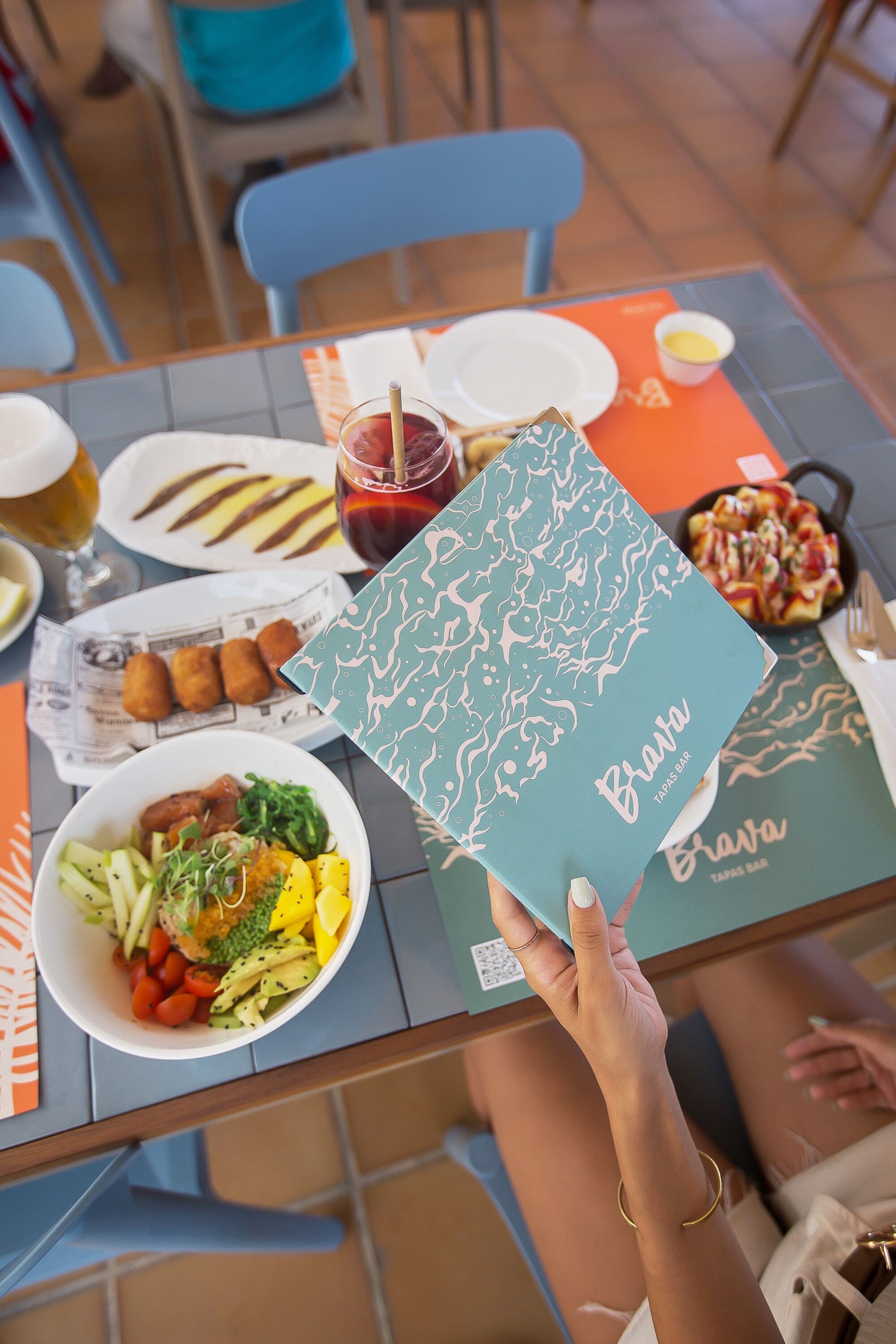 Une table avec différents plats, un menu et une boisson.