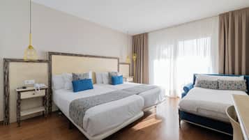 Habitación de hotel con dos camas, una mesita de noche, una lámpara y una ventana con cortinas.