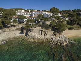 Un hotel costero con varios pisos, un litoral rocoso y aguas cristalinas.