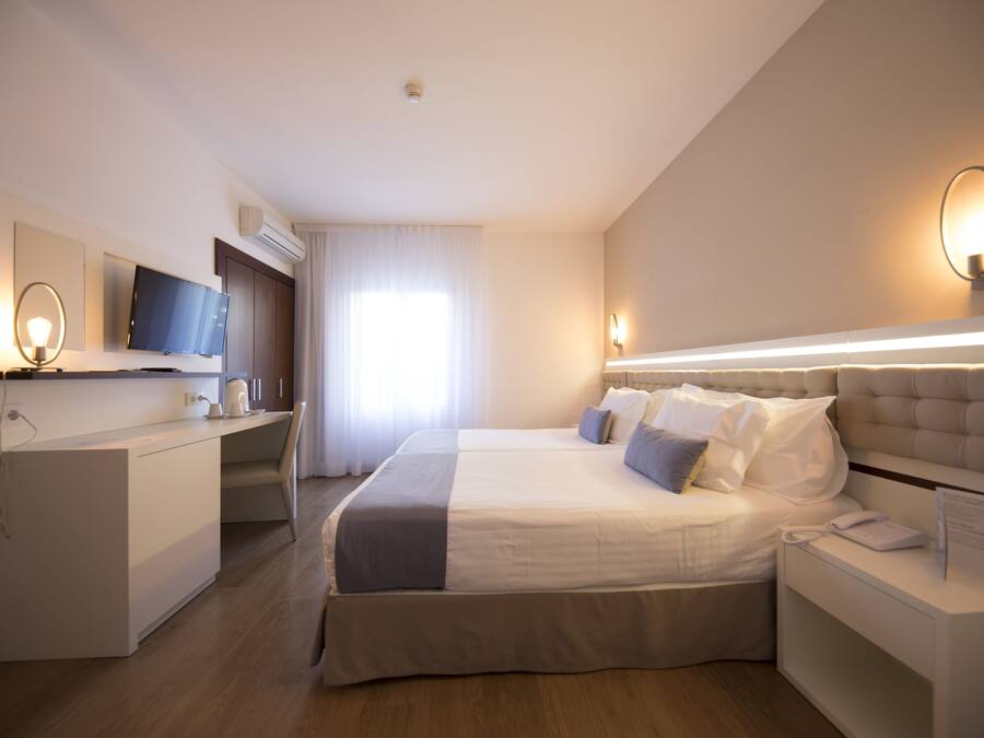 Ein modernes Hotelzimmer mit einem großen Bett, einem Schreibtisch, einem Flachbildfernseher und einem Nachttisch mit Lampe.