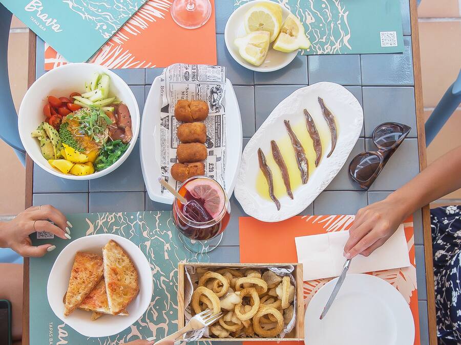 Una mesa de comedor con diversos platos, incluyendo una ensalada, comida frita y un plato de pescado.