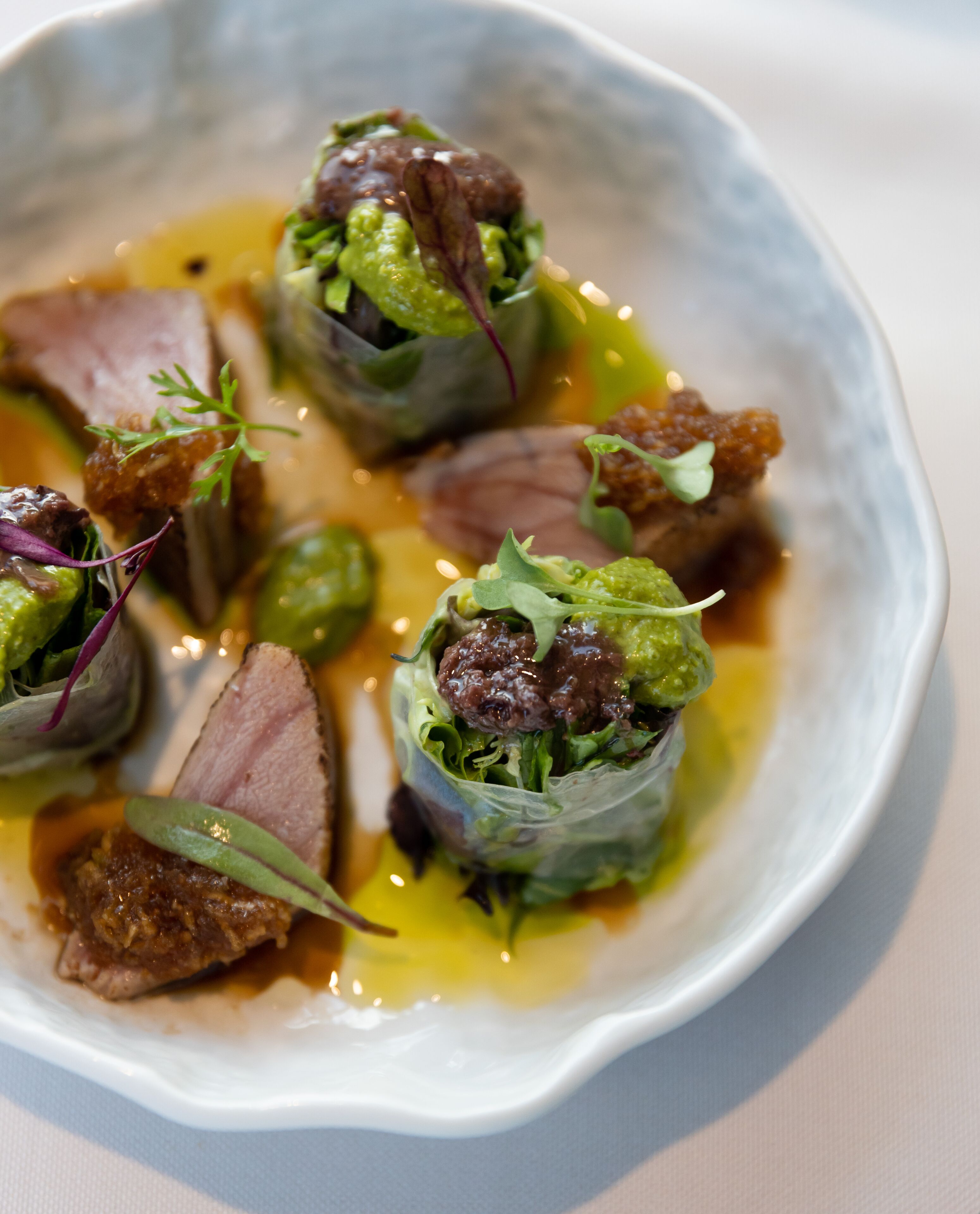 A plate of food with various dishes, including meat and greens, served on a white plate.