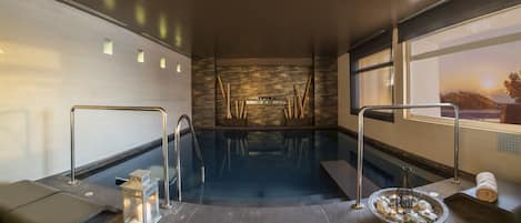 A spa area with a hot tub, seating, and a view of the sunset.
