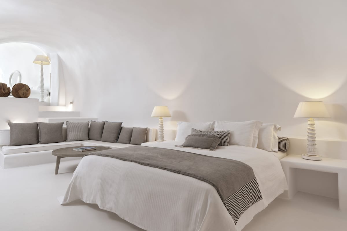 Ein schlicht eingerichtetes Schlafzimmer mit einem großen Bett, einer Couch und zwei Nachttischen mit Lampen.