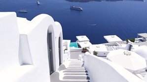 A white-walled building with a view of the sea and boats. - Katikies Chromata Santorini - The Leading Hotels of the World (Santorini)