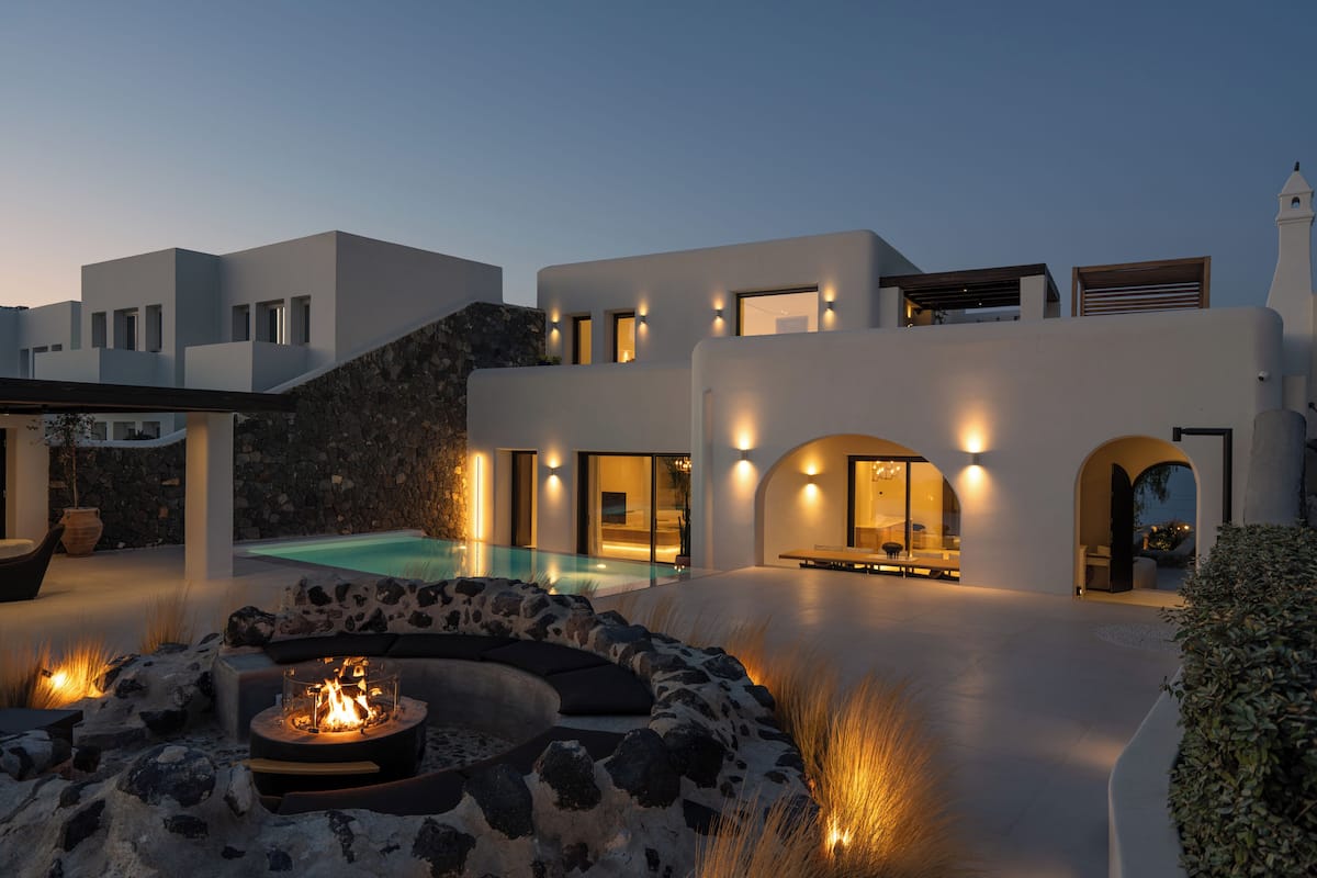 Eine moderne Villa mit Swimmingpool, Sitzgelegenheiten im Freien und einer Feuerstelle.