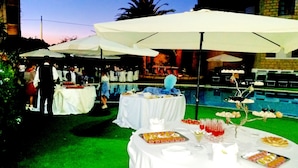 A poolside event with tables covered in white tablecloths, serving food and drinks. - Hotel Akrabello (Agrigento)