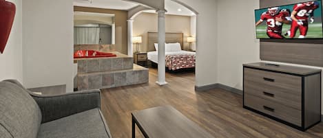 Habitación de hotel con sofá, televisión, escritorio y cama.