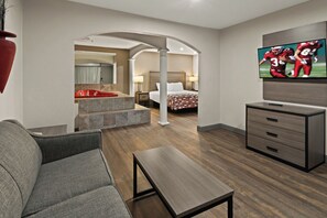 A hotel room with a sofa, a TV, a desk, and a bed.