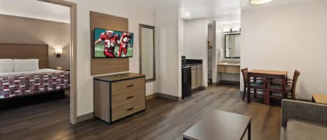 Een hotelkamer met een bed, een bureau, een stoel, een televisie en een kitchenette.