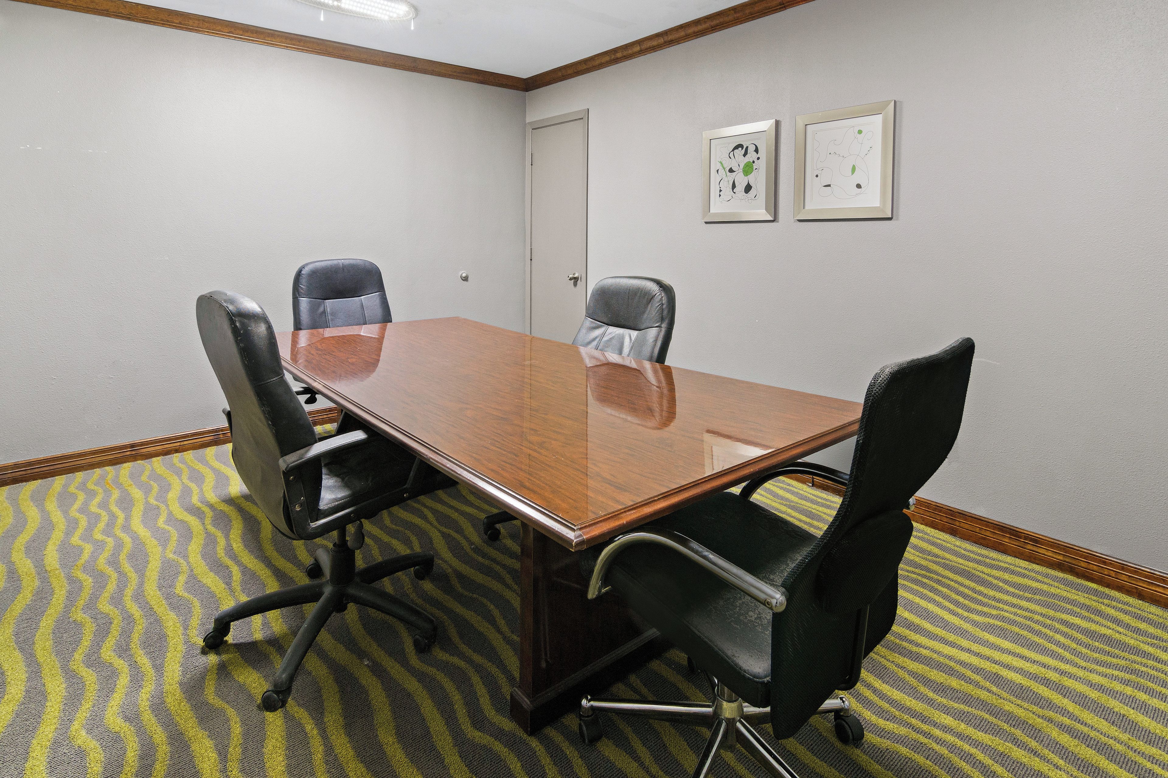 A conference room with a wooden table and four black office chairs.