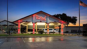 A Red Roof Inn & Suites with a prominent American flag, a parking lot, and a well-lit entrance.