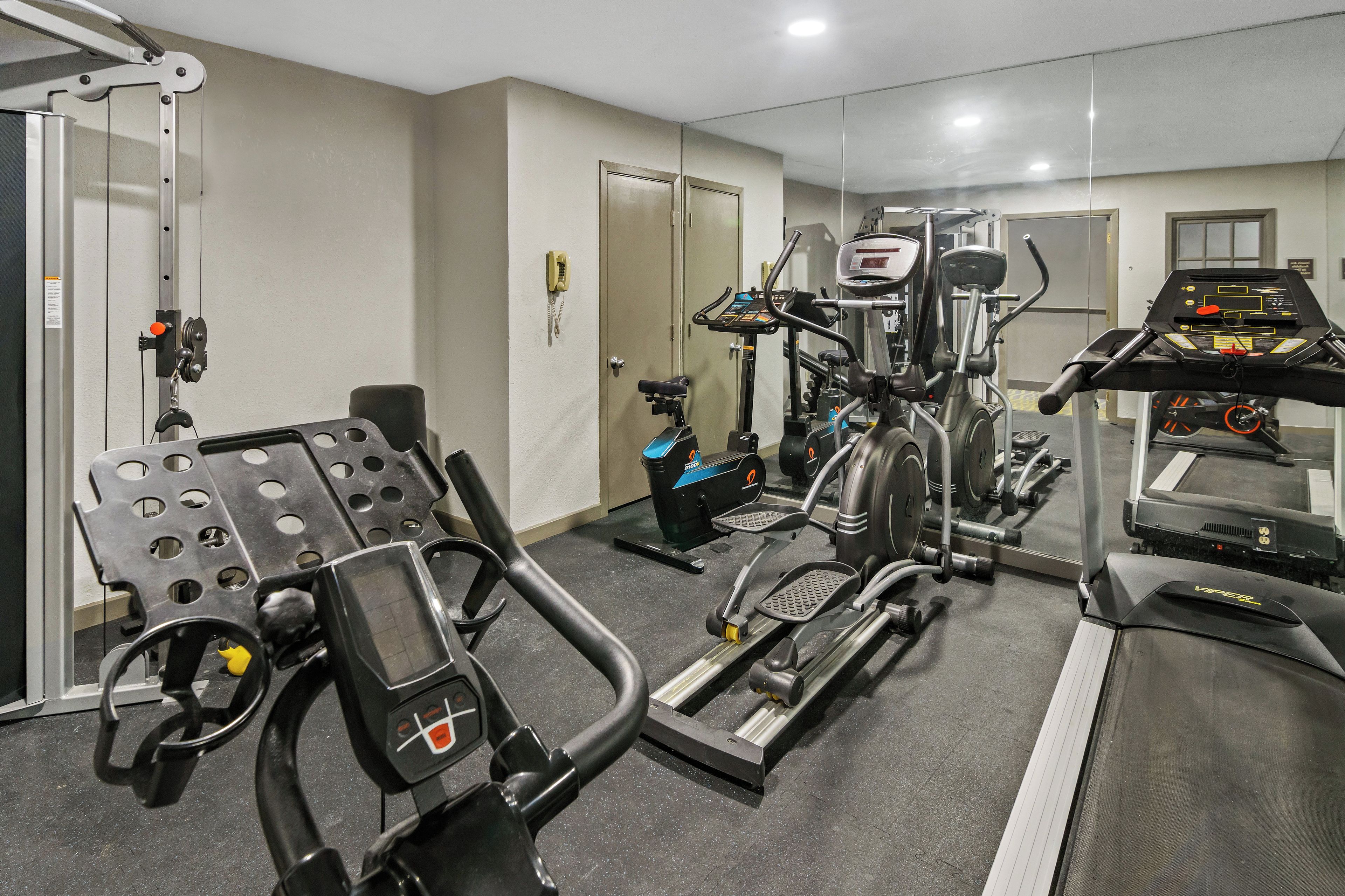 A gym with various exercise equipment including a treadmill, elliptical, and weight machines.