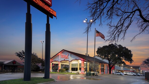 A Red Roof Inn & Suites with a large illuminated sign, an American flag, and a parking lot. - Red Roof Inn & Suites Irving – DFW Airport South  (Irving)