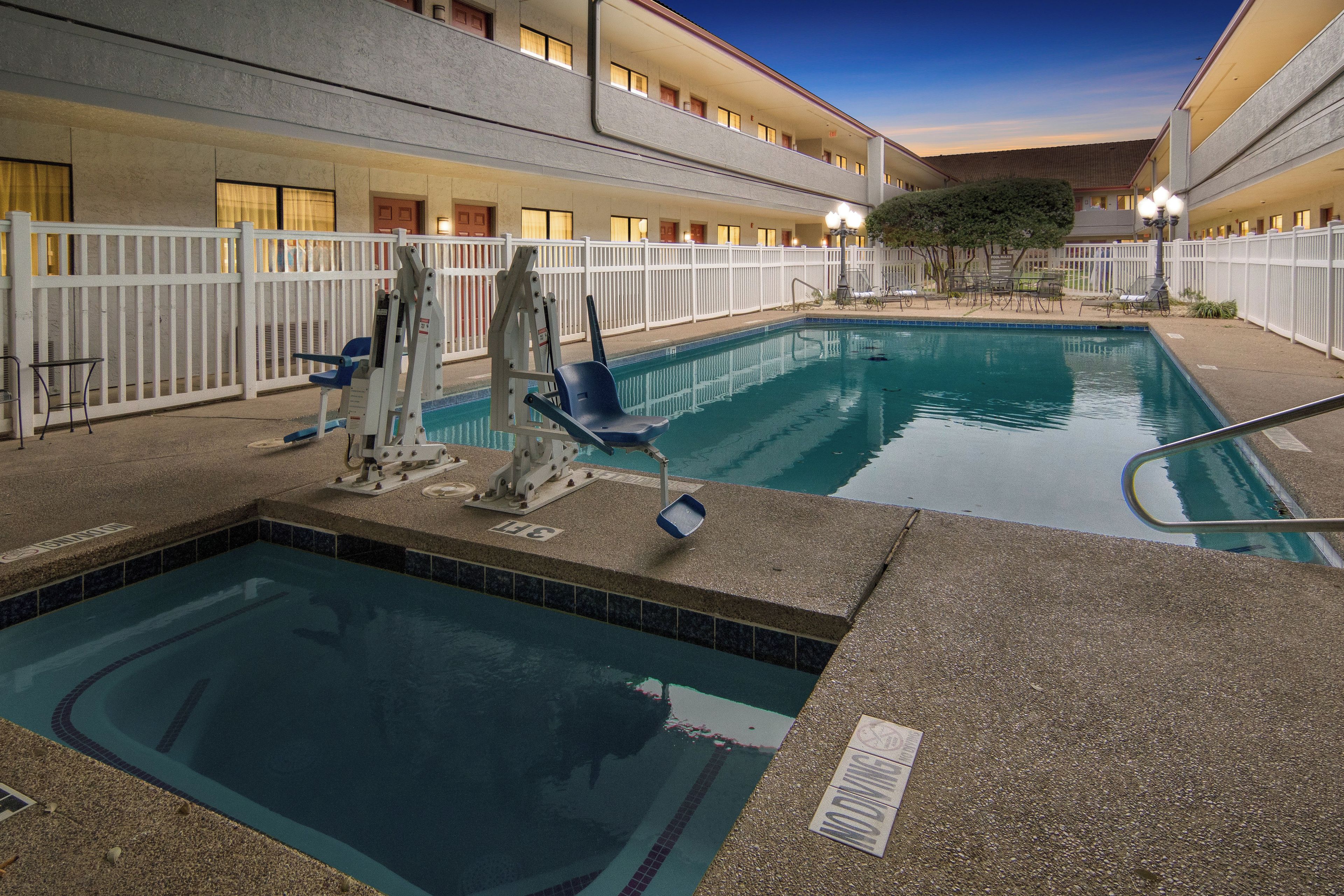 An indoor swimming pool with a lifeguard stand, lounge chairs, and a fenced area.