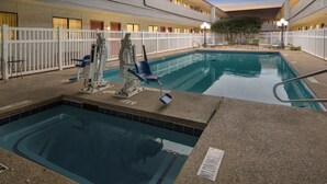 An indoor swimming pool with a lifeguard stand, lounge chairs, and a fenced area. - Red Roof Inn & Suites Irving – DFW Airport South  (Irving)
